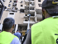 People and rescuers gather at the site of an Israeli airstrike that targets an apartment on al-Qaem Street in Beirut's southern suburbs on S...