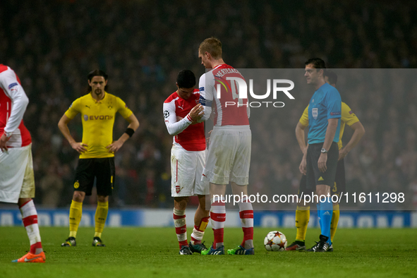 Mikel Arteta, captain of Arsenal, passes the captain's armband to teammate Per Mertesacker during the UEFA Champions League Group D soccer m...