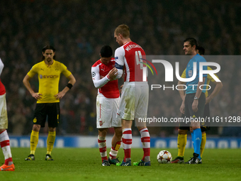 Mikel Arteta, captain of Arsenal, passes the captain's armband to teammate Per Mertesacker during the UEFA Champions League Group D soccer m...