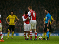 Mikel Arteta, captain of Arsenal, passes the captain's armband to teammate Per Mertesacker during the UEFA Champions League Group D soccer m...