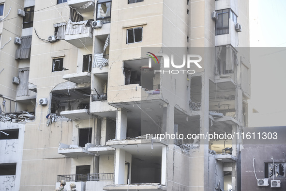 People and rescuers gather at the site of an Israeli airstrike that targets an apartment on al-Qaem Street in Beirut's southern suburbs on S...