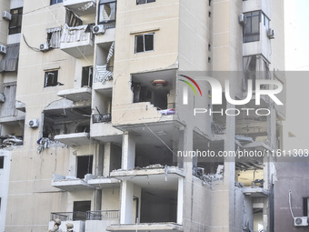 People and rescuers gather at the site of an Israeli airstrike that targets an apartment on al-Qaem Street in Beirut's southern suburbs on S...