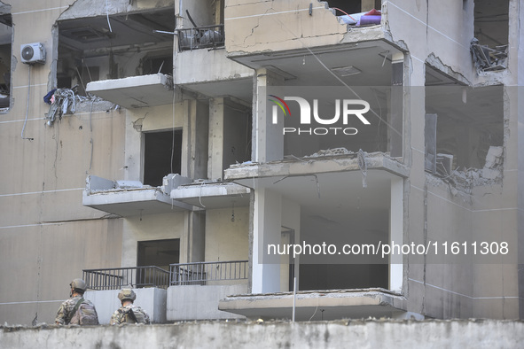 People and rescuers gather at the site of an Israeli airstrike that targets an apartment on al-Qaem Street in Beirut's southern suburbs on S...