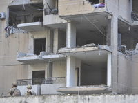 People and rescuers gather at the site of an Israeli airstrike that targets an apartment on al-Qaem Street in Beirut's southern suburbs on S...