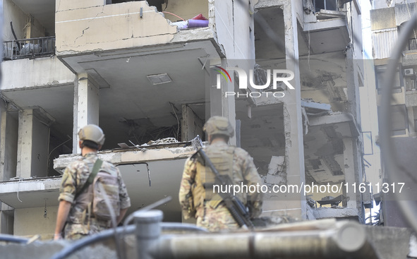 People and rescuers gather at the site of an Israeli airstrike that targets an apartment on al-Qaem Street in Beirut's southern suburbs on S...