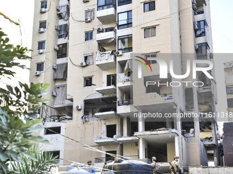 People and rescuers gather at the site of an Israeli airstrike that targets an apartment on al-Qaem Street in Beirut's southern suburbs on S...