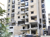 People and rescuers gather at the site of an Israeli airstrike that targets an apartment on al-Qaem Street in Beirut's southern suburbs on S...