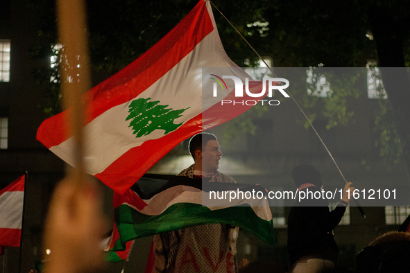 A protester holds a Palestinian flag with a waving Lebanese flag behind him during the Lebanon Ceasefire Protest at 10 Downing Street in Lon...