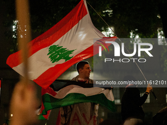 A protester holds a Palestinian flag with a waving Lebanese flag behind him during the Lebanon Ceasefire Protest at 10 Downing Street in Lon...