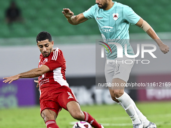 Mahmoud Hassan (R) of Al Rayyan SC battles for the ball with Abdulla Hassan Al-Marafi (L) of Al Arabi SC during the Ooredoo Qatar Stars Leag...