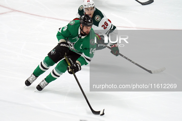 Jamie Benn #14 of the Dallas Stars skates with control of the puck while defended by Liam Ohgren #28 of the Minnesota Wild during the NHL pr...