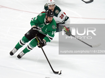 Jamie Benn #14 of the Dallas Stars skates with control of the puck while defended by Liam Ohgren #28 of the Minnesota Wild during the NHL pr...