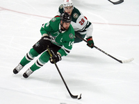 Jamie Benn #14 of the Dallas Stars skates with control of the puck while defended by Liam Ohgren #28 of the Minnesota Wild during the NHL pr...