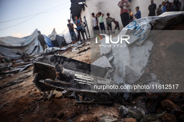 People stand amidst the destruction after a reported overnight Israeli strike that hits tents used as temporary shelters by displaced Palest...