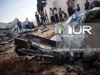 People stand amidst the destruction after a reported overnight Israeli strike that hits tents used as temporary shelters by displaced Palest...