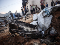 People stand amidst the destruction after a reported overnight Israeli strike that hits tents used as temporary shelters by displaced Palest...