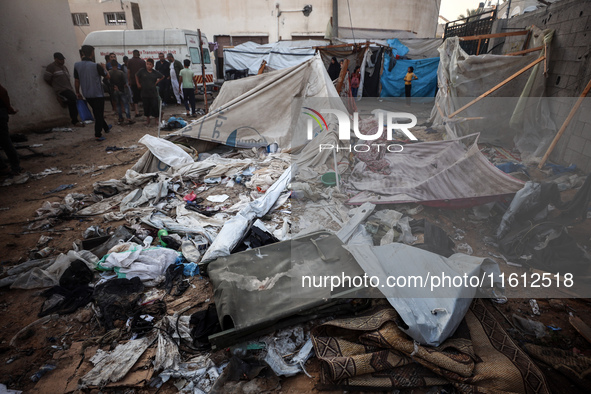 People stand amidst the destruction after a reported overnight Israeli strike that hits tents used as temporary shelters by displaced Palest...