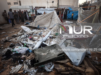 People stand amidst the destruction after a reported overnight Israeli strike that hits tents used as temporary shelters by displaced Palest...