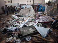 People stand amidst the destruction after a reported overnight Israeli strike that hits tents used as temporary shelters by displaced Palest...