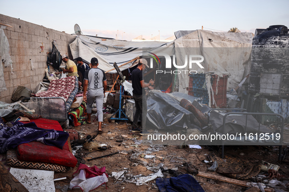 People stand amidst the destruction after a reported overnight Israeli strike that hits tents used as temporary shelters by displaced Palest...