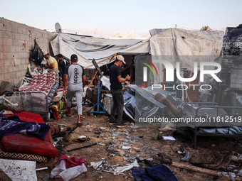 People stand amidst the destruction after a reported overnight Israeli strike that hits tents used as temporary shelters by displaced Palest...