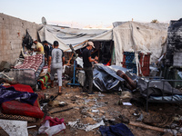 People stand amidst the destruction after a reported overnight Israeli strike that hits tents used as temporary shelters by displaced Palest...