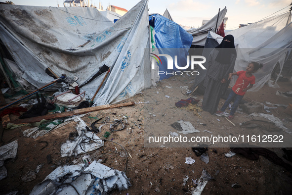 People stand amidst the destruction after a reported overnight Israeli strike that hits tents used as temporary shelters by displaced Palest...