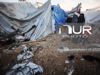 People stand amidst the destruction after a reported overnight Israeli strike that hits tents used as temporary shelters by displaced Palest...