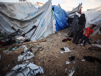 People stand amidst the destruction after a reported overnight Israeli strike that hits tents used as temporary shelters by displaced Palest...