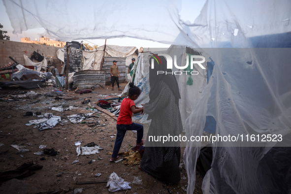 People stand amidst the destruction after a reported overnight Israeli strike that hits tents used as temporary shelters by displaced Palest...