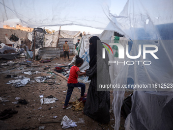 People stand amidst the destruction after a reported overnight Israeli strike that hits tents used as temporary shelters by displaced Palest...