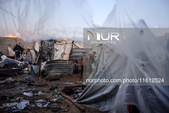 People stand amidst the destruction after a reported overnight Israeli strike that hits tents used as temporary shelters by displaced Palest...