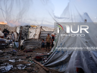 People stand amidst the destruction after a reported overnight Israeli strike that hits tents used as temporary shelters by displaced Palest...