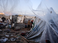 People stand amidst the destruction after a reported overnight Israeli strike that hits tents used as temporary shelters by displaced Palest...