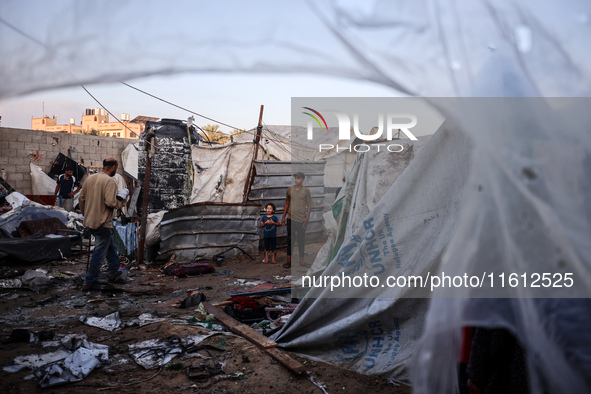 People stand amidst the destruction after a reported overnight Israeli strike that hits tents used as temporary shelters by displaced Palest...