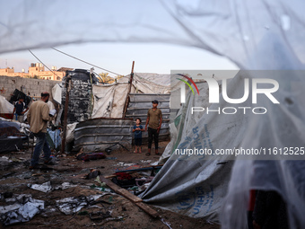 People stand amidst the destruction after a reported overnight Israeli strike that hits tents used as temporary shelters by displaced Palest...