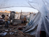 People stand amidst the destruction after a reported overnight Israeli strike that hits tents used as temporary shelters by displaced Palest...