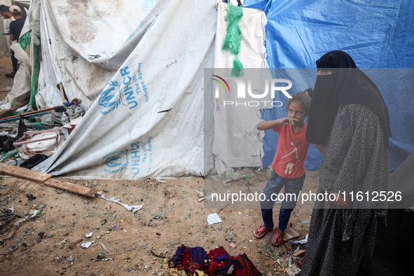 People stand amidst the destruction after a reported overnight Israeli strike that hits tents used as temporary shelters by displaced Palest...