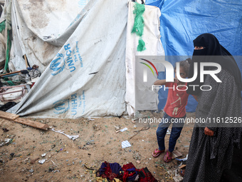 People stand amidst the destruction after a reported overnight Israeli strike that hits tents used as temporary shelters by displaced Palest...