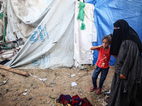 People stand amidst the destruction after a reported overnight Israeli strike that hits tents used as temporary shelters by displaced Palest...