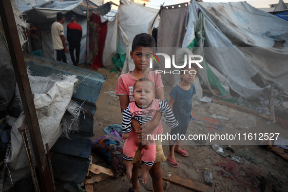 Children stand in the midst of the destruction in the aftermath of a reported overnight Israeli strike that hits tents used as temporary she...