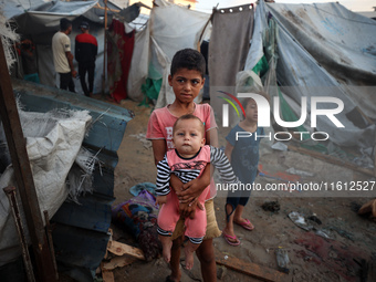 Children stand in the midst of the destruction in the aftermath of a reported overnight Israeli strike that hits tents used as temporary she...