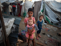 Children stand in the midst of the destruction in the aftermath of a reported overnight Israeli strike that hits tents used as temporary she...