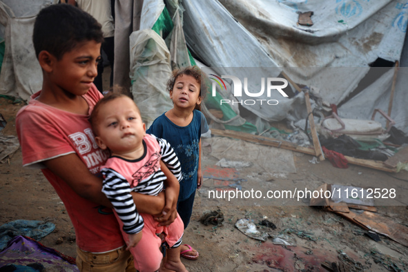 Children stand in the midst of the destruction in the aftermath of a reported overnight Israeli strike that hits tents used as temporary she...