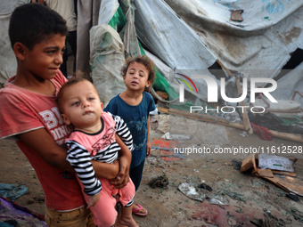 Children stand in the midst of the destruction in the aftermath of a reported overnight Israeli strike that hits tents used as temporary she...