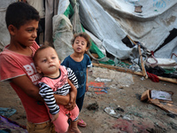 Children stand in the midst of the destruction in the aftermath of a reported overnight Israeli strike that hits tents used as temporary she...