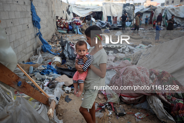 Children stand in the midst of the destruction in the aftermath of a reported overnight Israeli strike that hits tents used as temporary she...