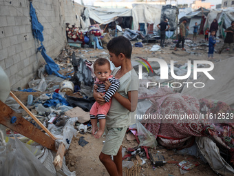 Children stand in the midst of the destruction in the aftermath of a reported overnight Israeli strike that hits tents used as temporary she...