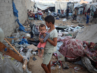 Children stand in the midst of the destruction in the aftermath of a reported overnight Israeli strike that hits tents used as temporary she...