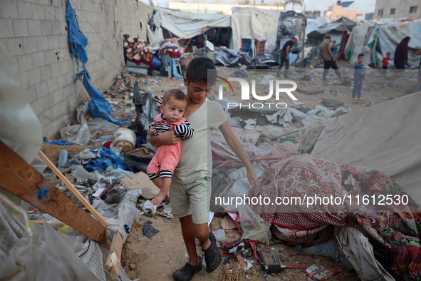 Children stand in the midst of the destruction in the aftermath of a reported overnight Israeli strike that hits tents used as temporary she...